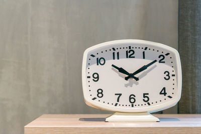 Close-up of clock on table against wall