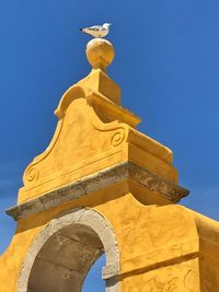 Low angle view of bell tower against blue sky