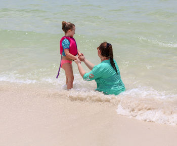 Full length of mother and daughter on beach