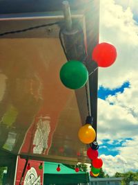 Low angle view of balloons hanging against sky