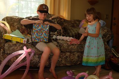 Boy opening gift with sister at home