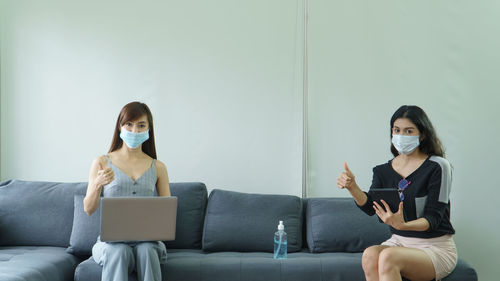 Young woman using phone while sitting on sofa