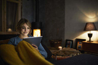 Portrait of smiling woman with tablet relaxing on couch in the evening