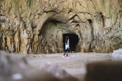 Rear view of woman standing in cave