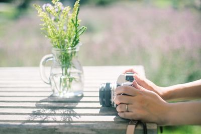 Midsection of woman photographing flower on table