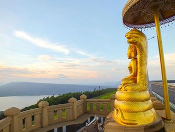 Golden statue of buddha against sky during sunset