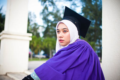 Portrait of beautiful young woman standing against built structure