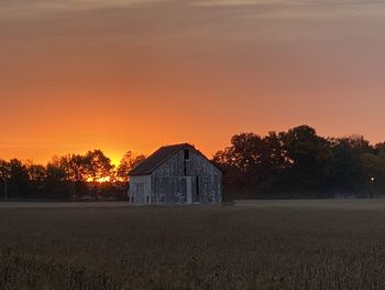 House on field against sky during sunset