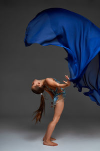 Rear view of woman with arms raised standing against black background