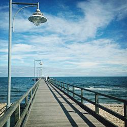 Pier on sea against cloudy sky