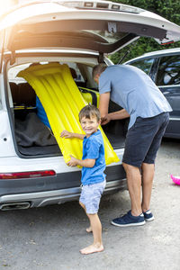 Father with son keeping pool raft in car