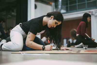 Female activist preparing signboard while sitting in building to protest against social issues