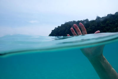 Cropped hand of person swimming in sea