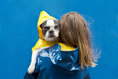 Portrait of woman with dog against blue background