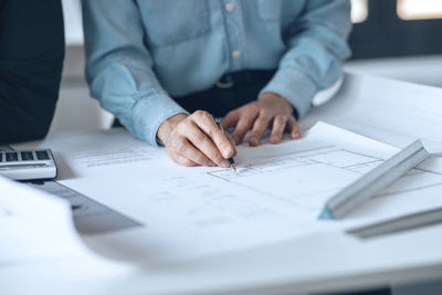 Architect holding pen on document in small office