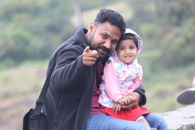 Portrait of father with cute daughter sitting outdoors