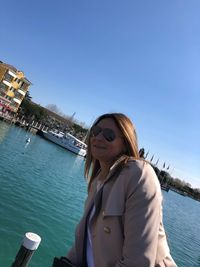 Portrait of smiling young woman in boat against sky