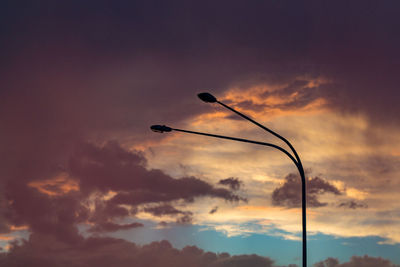 Low angle view of silhouette street light against dramatic sky