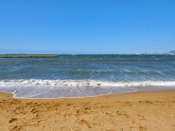 Scenic view of beach against clear blue sky