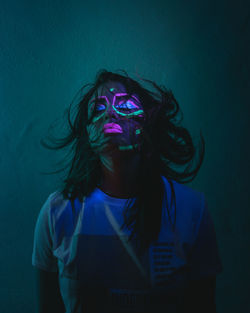 Portrait of young woman wearing mask against gray background