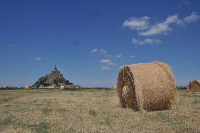 Hay bales on field against sky