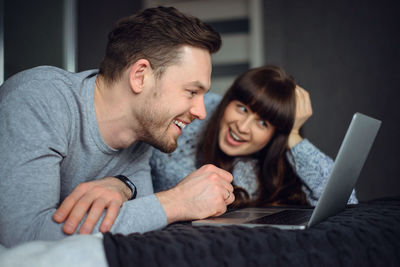 Smiling couple looking at laptop while sitting on sofa