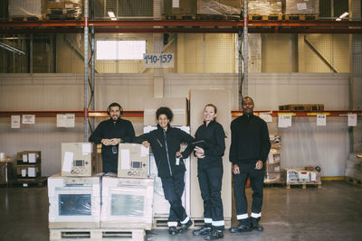 Portrait of smiling warehouse workers standing with box containers