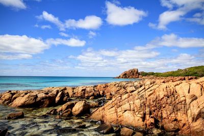 Rock formations on beach against sky