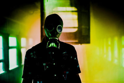 Teenage boy wearing gas mask while standing amidst smoke