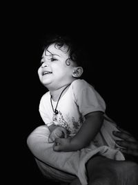 Cute girl sitting against black background