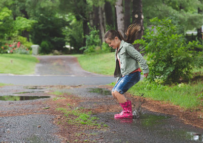 Young girl jumping into puddle