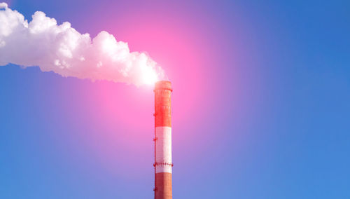 Smoke emitting from chimney against blue sky