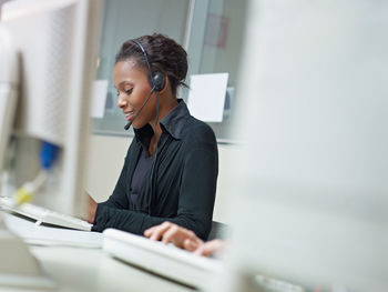 Smiling businesswoman using computer on desk in office