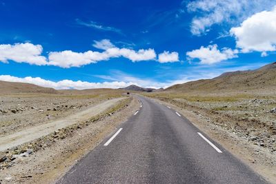 Road leading towards mountains against sky