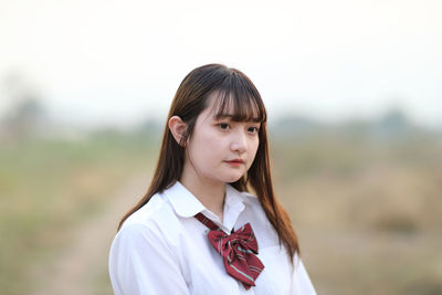 Portrait of young woman standing against sky