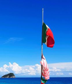 Flag on sea against blue sky