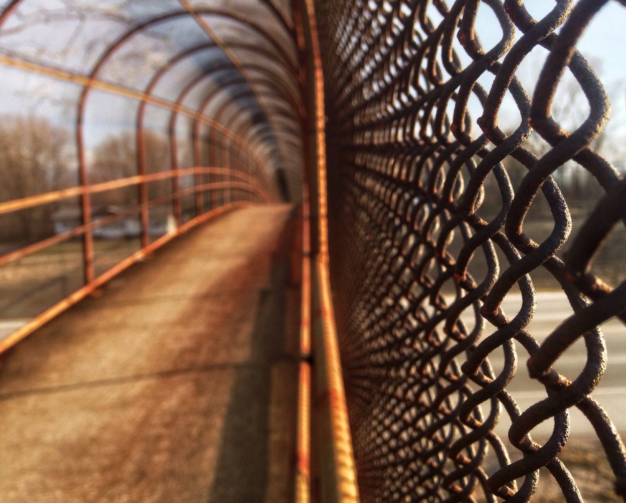 the way forward, diminishing perspective, metal, vanishing point, pattern, transportation, railing, metallic, built structure, chainlink fence, architecture, protection, sunlight, no people, day, fence, connection, indoors, railroad track, safety