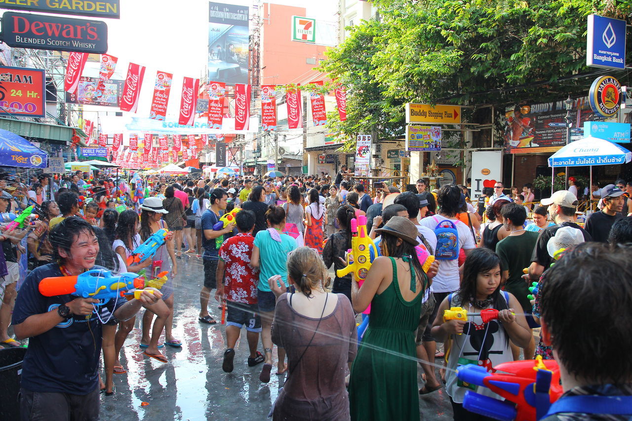 GROUP OF PEOPLE ON STREET BY BUILDINGS IN CITY