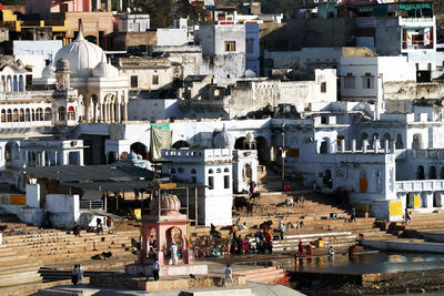 High angle view of people at temple by lake and white buildings