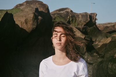 Young woman sitting on rock at beach