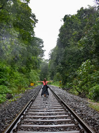 Rear view of woman on railroad track against sky