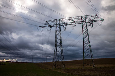 Low angle view of electricity pylon on field against sky