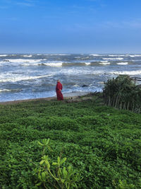 Rear view of woman standing on beach against sky