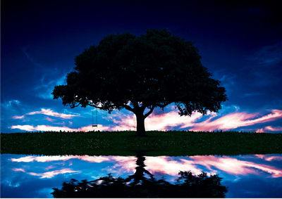 Silhouette tree by lake against sky at night