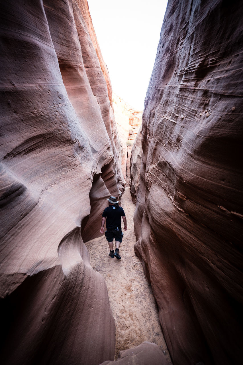 REAR VIEW OF MAN ON ROCKS