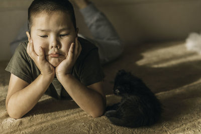 Portrait of an asian boy lying sad with a kitten