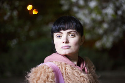 Portrait of woman wearing fur coat against trees