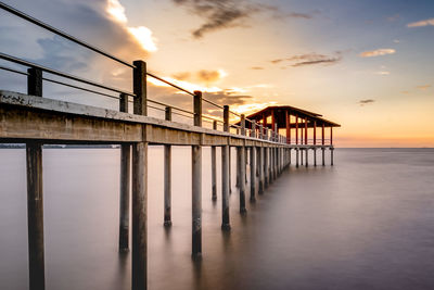 Pier over sea against sky during sunset