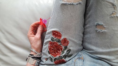 Midsection of woman wearing torn jeans while sitting on sofa at home