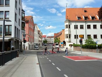 People on road amidst buildings in city against sky